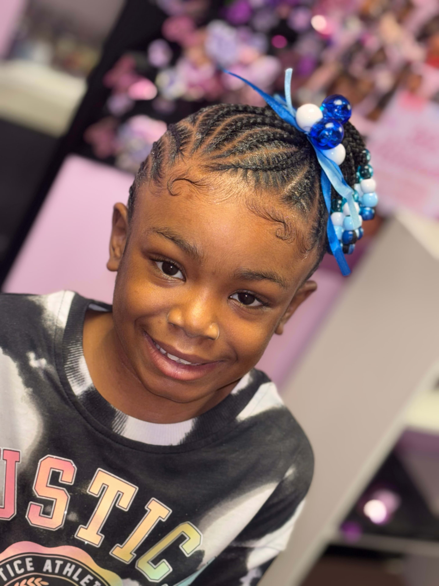 Smiling child with fresh cornrows and blue beads at 360 Attitude Children's Salon